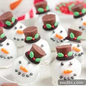 Oreo balls made to look like snowman heads with face and hat on white plate.