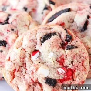 Oreo cookies baked into white chocolate peppermint cookies with candy cane pieces on white plate.