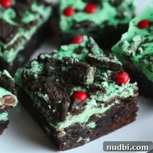 Green mint iced brownies with crushed Oreos and red candies on top.