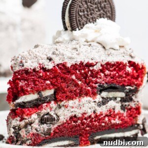 Slice of red velvet cake with Oreos in layers and cookies and cream frosting.