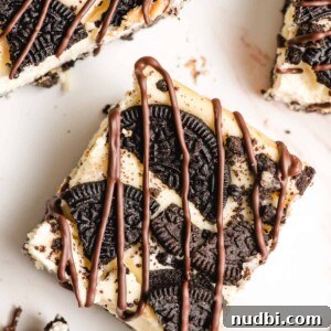 Oreo cheesecake bars sliced on counter and drizzled with chocolate.