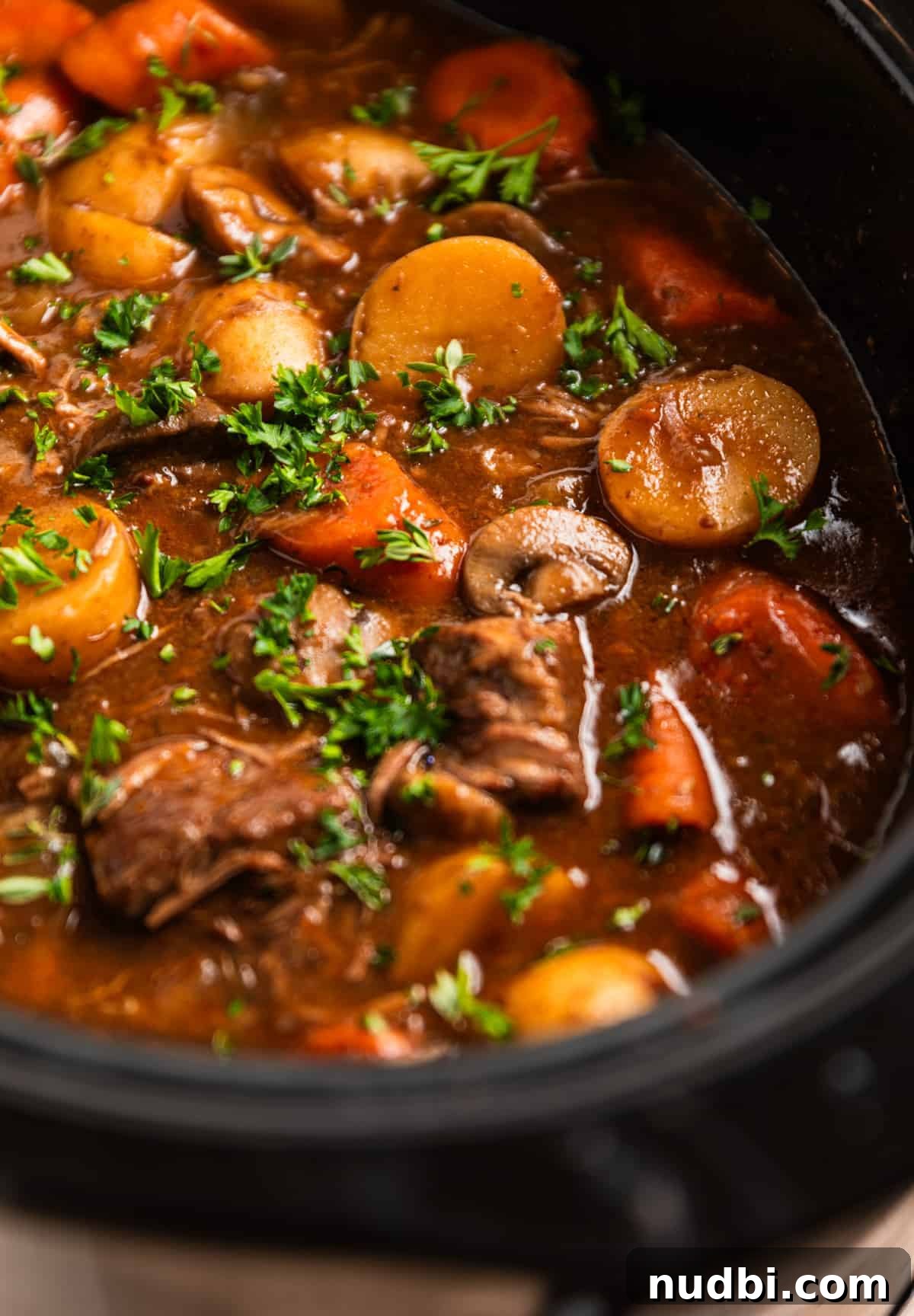 Slow Cooker Beef and Mushroom Stew Recipe for Tender Comfort Food 4 Crockpot with beef stew cooked and topped with freshly chopped parsley.