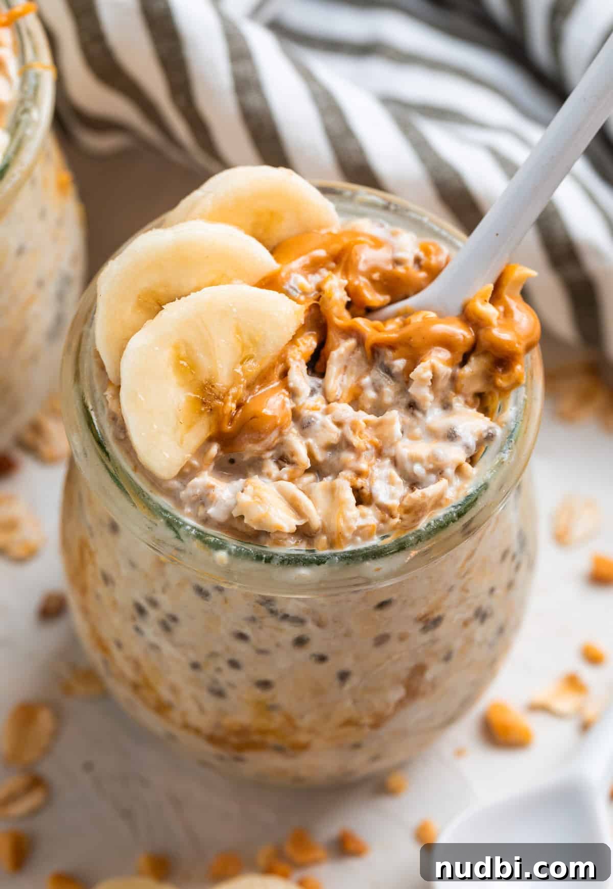 High-Protein Overnight Oats Recipe for Busy Mornings 5 Spoon in jar of overnight oatmeal with peanut butter and banana.