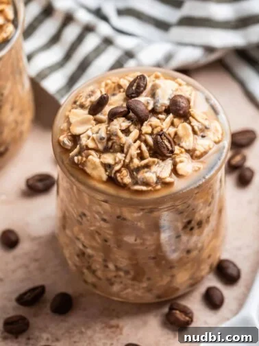 Vanilla cold brew coffee overnight oats in jar with spoon beside it and napkin behind.