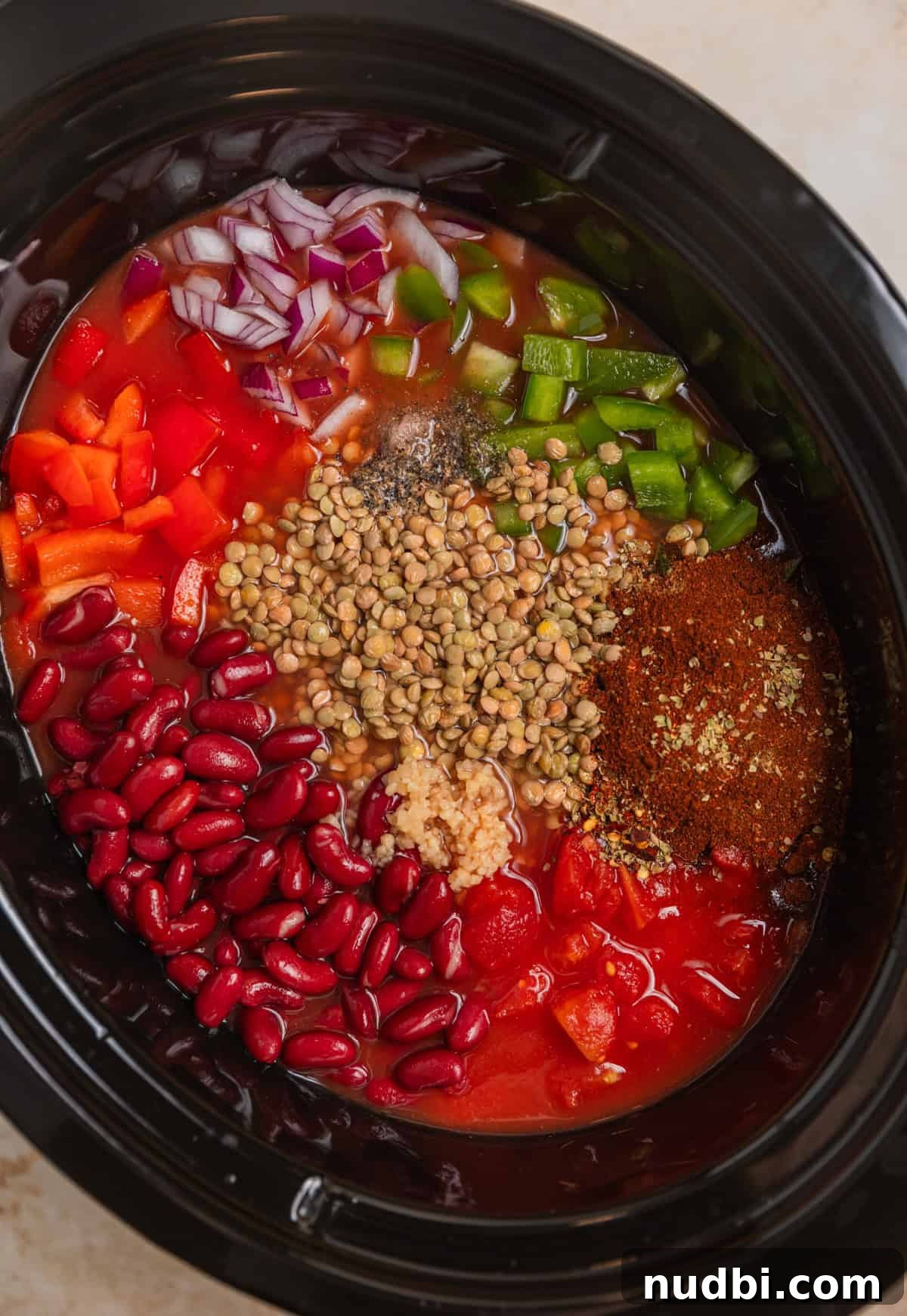 Slow-Cooker Lentil Chili Recipe for Comforting Weeknight Meals 3 Lentils, kidney beans, green peppers, spices and other chili ingredients arranged in crock pot before cooking.