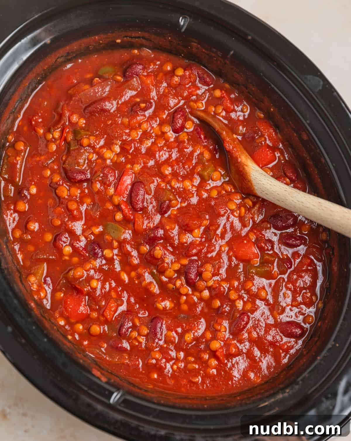 Slow-Cooker Lentil Chili Recipe for Comforting Weeknight Meals 6 Slow cooker lentil chili prepared in pot with wooden spoon.