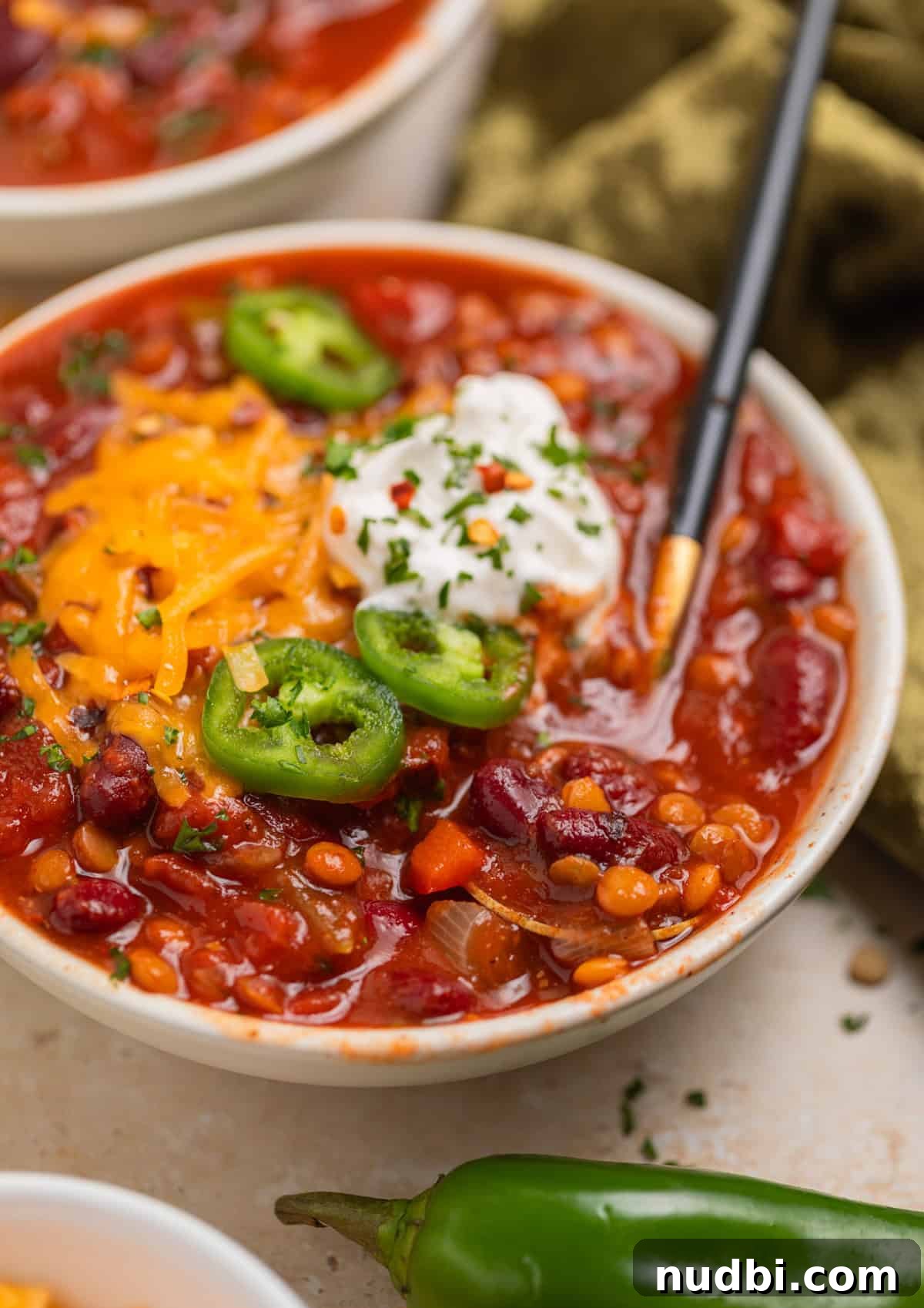 Slow-Cooker Lentil Chili Recipe for Comforting Weeknight Meals 7 Bowl of lentil chili with spoon scooping into it.