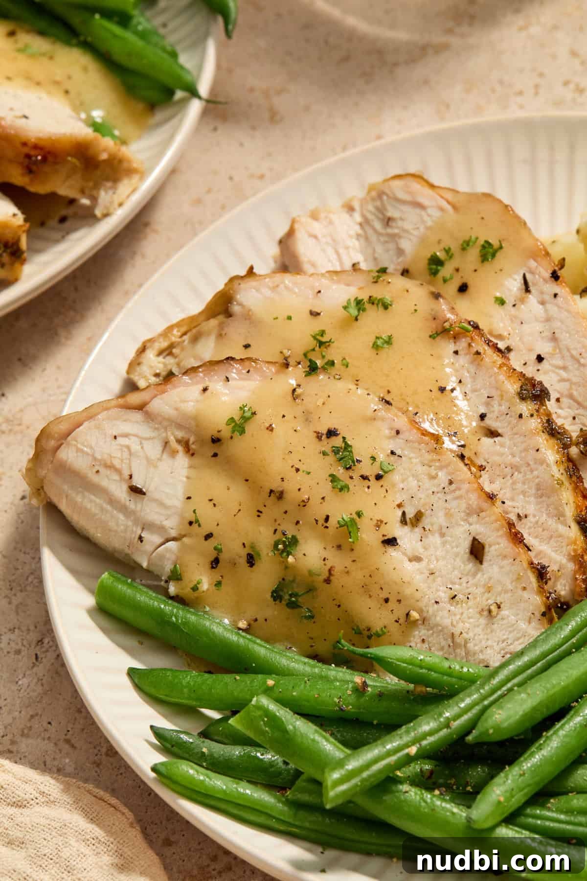 Juicy Slow Cooker Turkey Breast Recipe 13 Sliced turkey breast on plate with green beans and gravy on top.