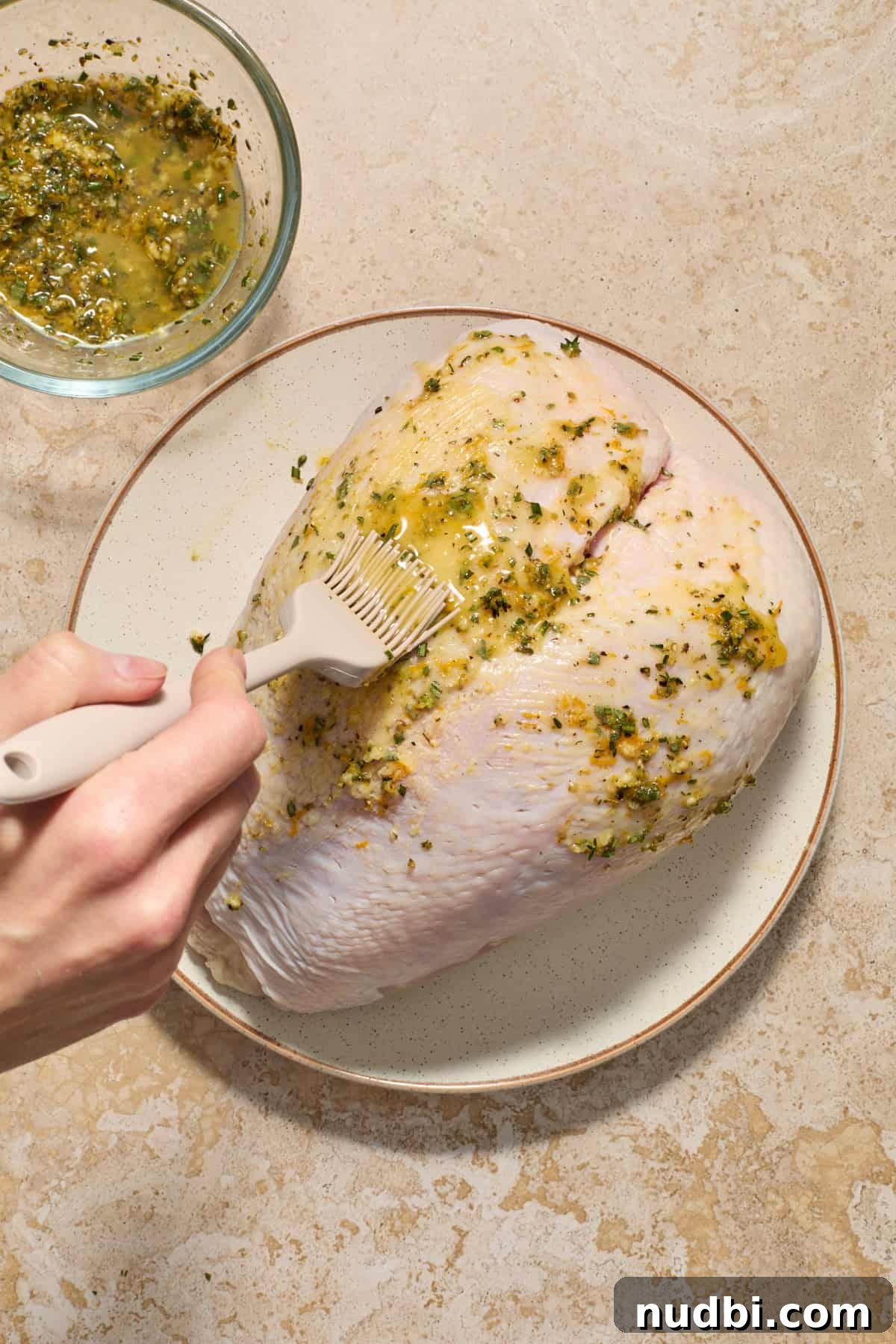 Juicy Slow Cooker Turkey Breast Recipe 6 Bone in turkey breast with herb butter being brushed onto it.