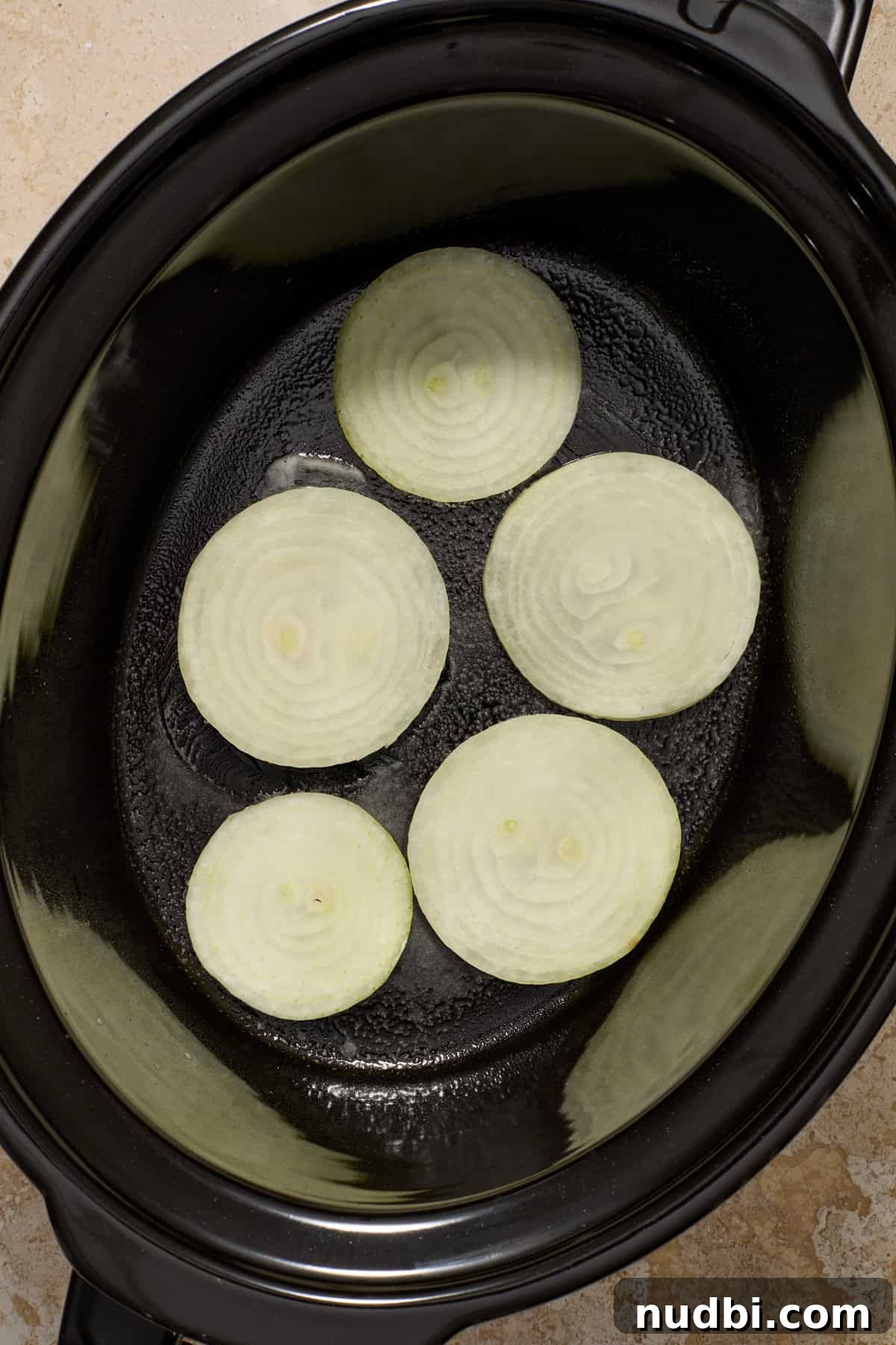 Juicy Slow Cooker Turkey Breast Recipe 7 Sliced onions at the bottom of slow cooker pot.