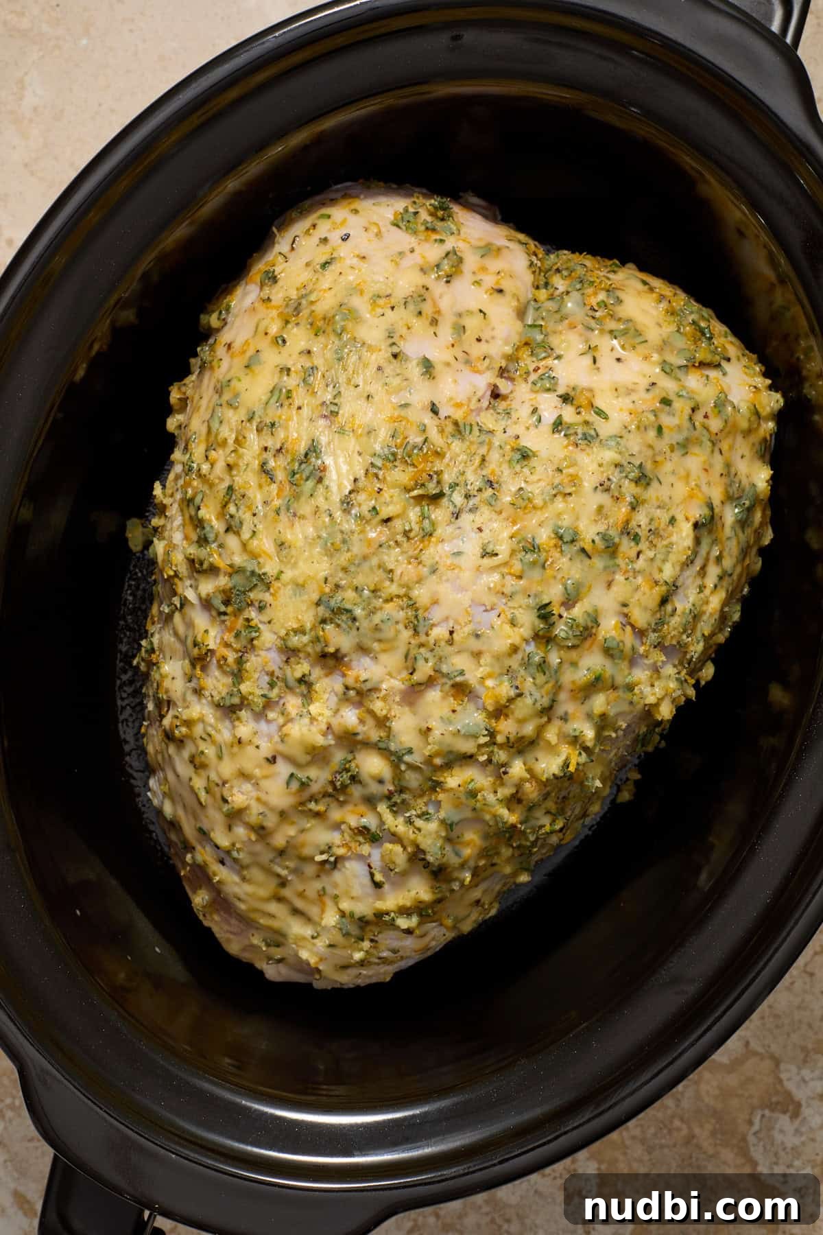 Juicy Slow Cooker Turkey Breast Recipe 8 Herb and butter rubbed bone in turkey breast in slow cooker pot before cooking.