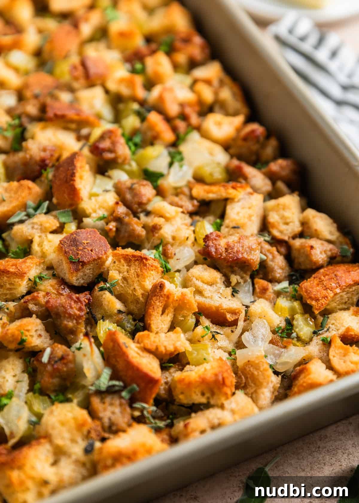 Turkey Sausage Stuffing Recipe for Thanksgiving and Holiday Meals 16 Turkey sausage stuffing baked in pan topped with fresh herbs.
