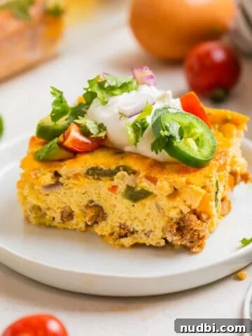 Chorizo egg bake slice topped with sour cream, cilantro, tomato and jalapeño.