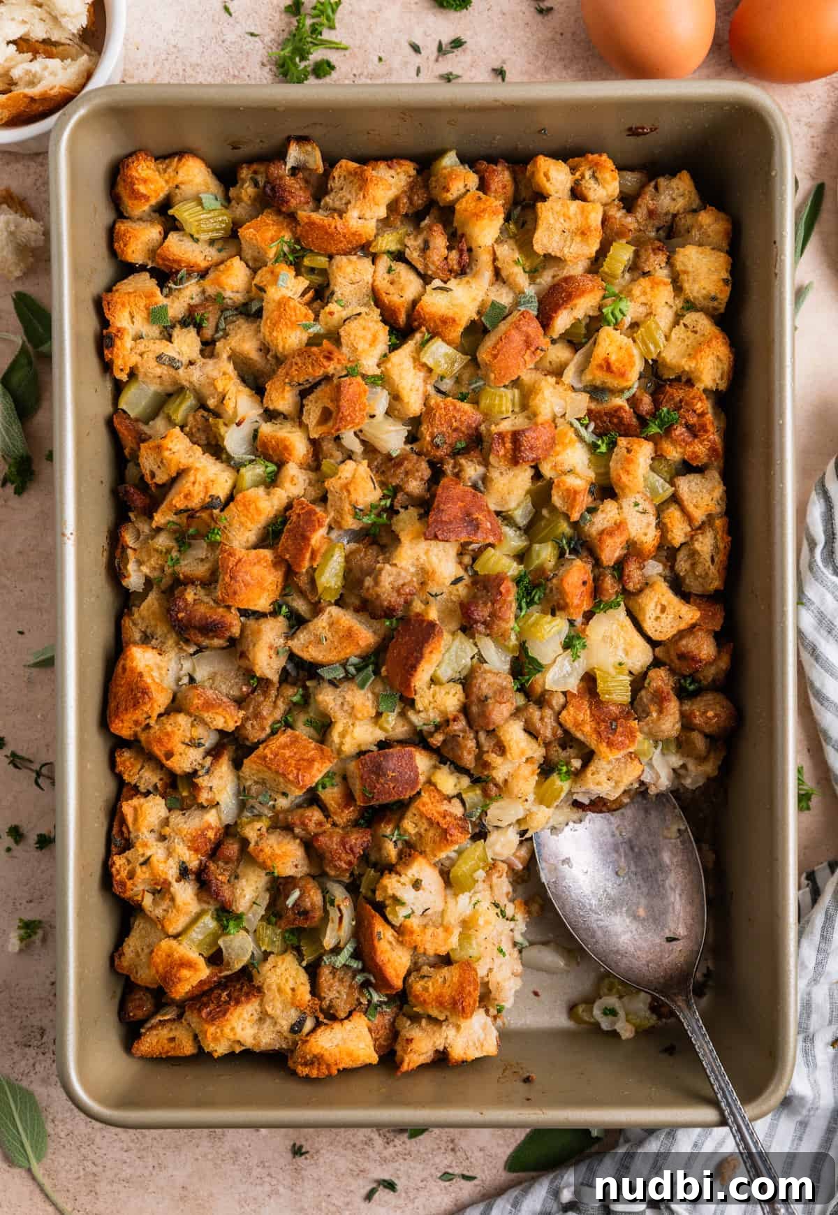 Turkey Sausage Stuffing Recipe for Thanksgiving and Holiday Meals 4 Overhead view of pan with turkey sausage stuffing and serving spoon scooping into the pan.