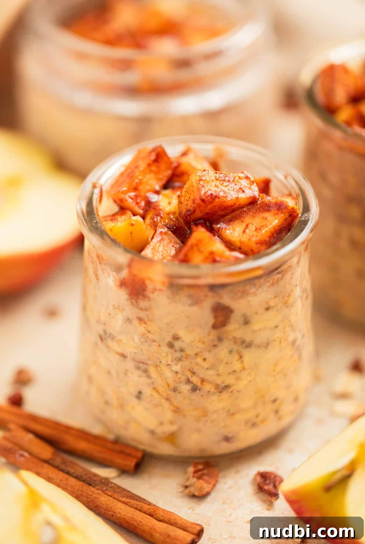 Apple Cinnamon Overnight Oats Recipe for Quick Breakfast 2 Cinnamon apple overnight oats in jar with apples and cinnamon sticks around them.