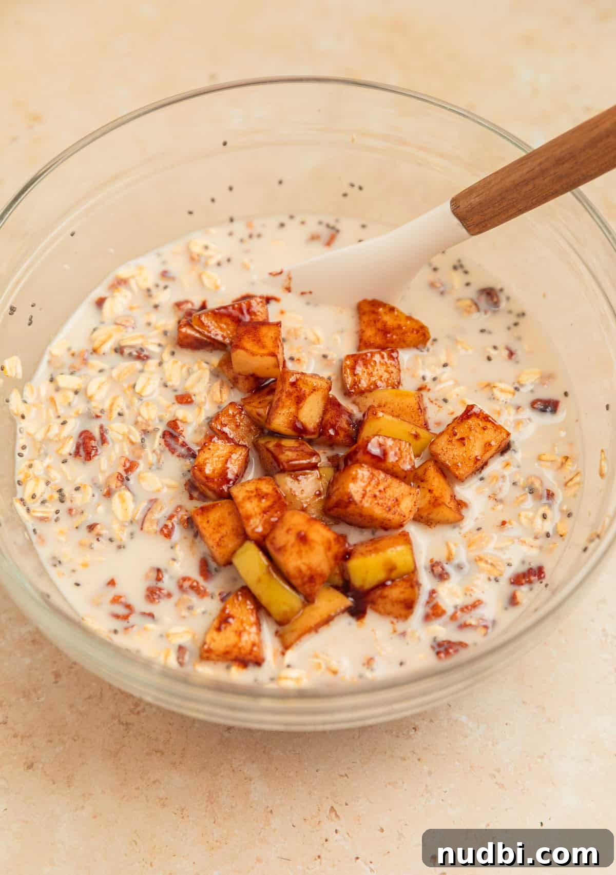 Apple Cinnamon Overnight Oats Recipe for Quick Breakfast 8 Cinnamon apples added to overnight oatmeal mixture in glass bowl.