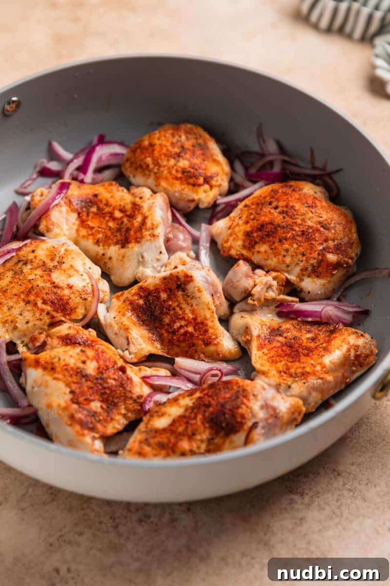 Sheet Pan Chicken Thighs with Roasted Brussels Sprouts 5 Seared chicken thighs and red onion in skillet.