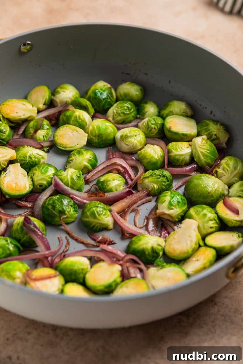 Sheet Pan Chicken Thighs with Roasted Brussels Sprouts 6 Brussels sprouts and red onion sautéed in skillet.