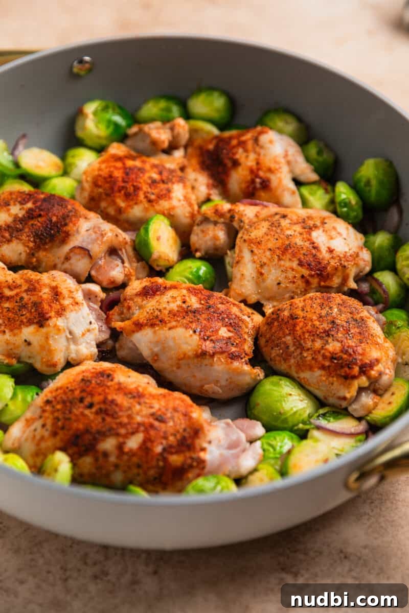 Sheet Pan Chicken Thighs with Roasted Brussels Sprouts 7 Chicken thighs and Brussel sprouts being cooked in gray skillet.
