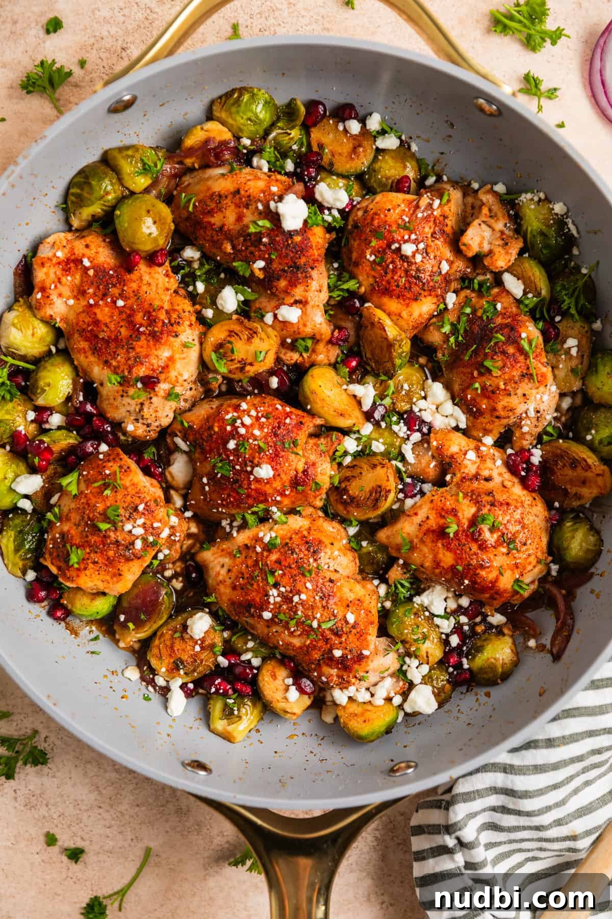 Sheet Pan Chicken Thighs with Roasted Brussels Sprouts 9 Overhead view of one pan chicken thighs and vegetables topped with chopped parsley, goat cheese and pomegranate arils.