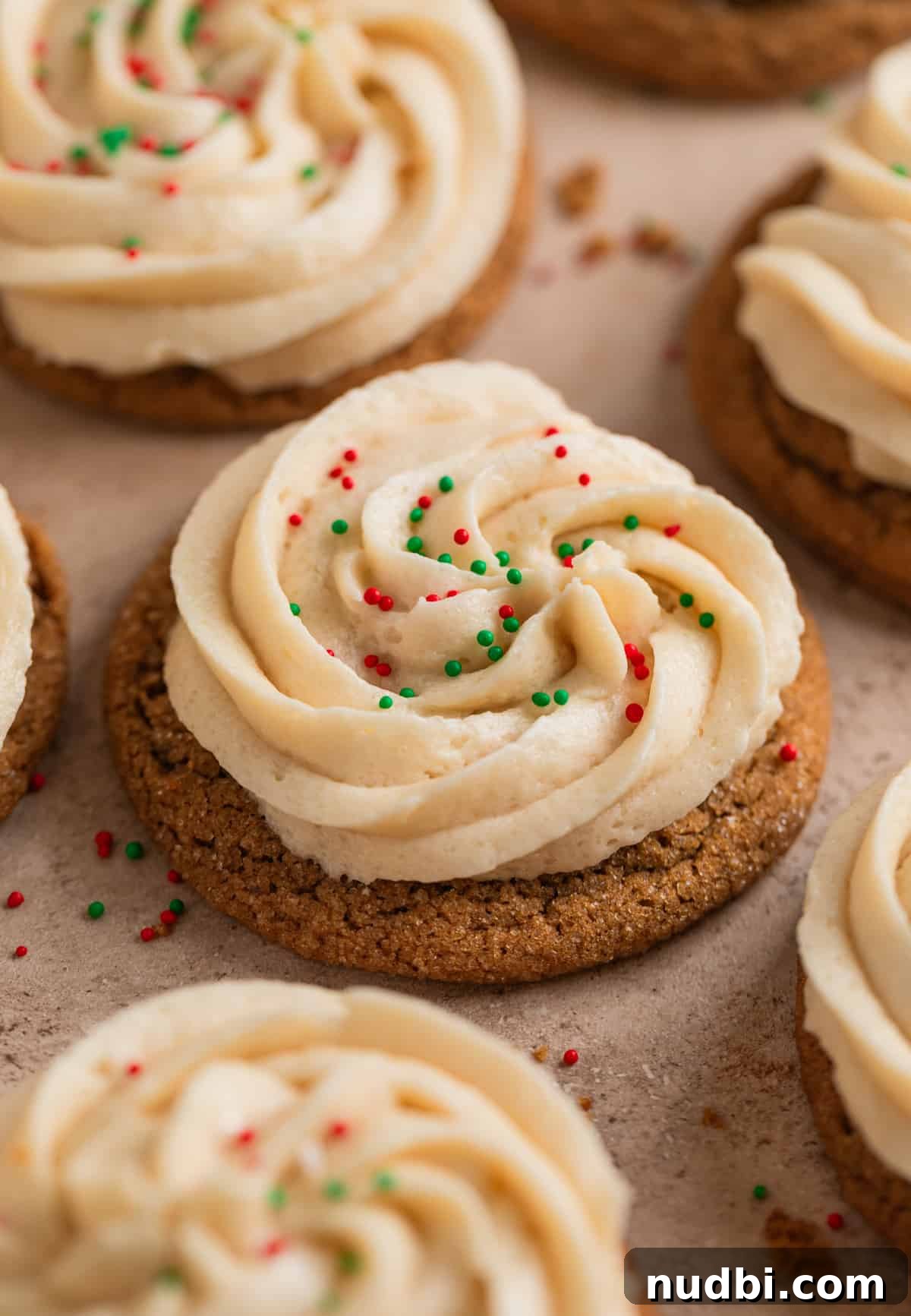 Chewy Ginger Cream Cookie Recipe for Perfect Holiday Baking 2 Ginger cream cookies with brown sugar buttercream frosting and festive sprinkles on surface.