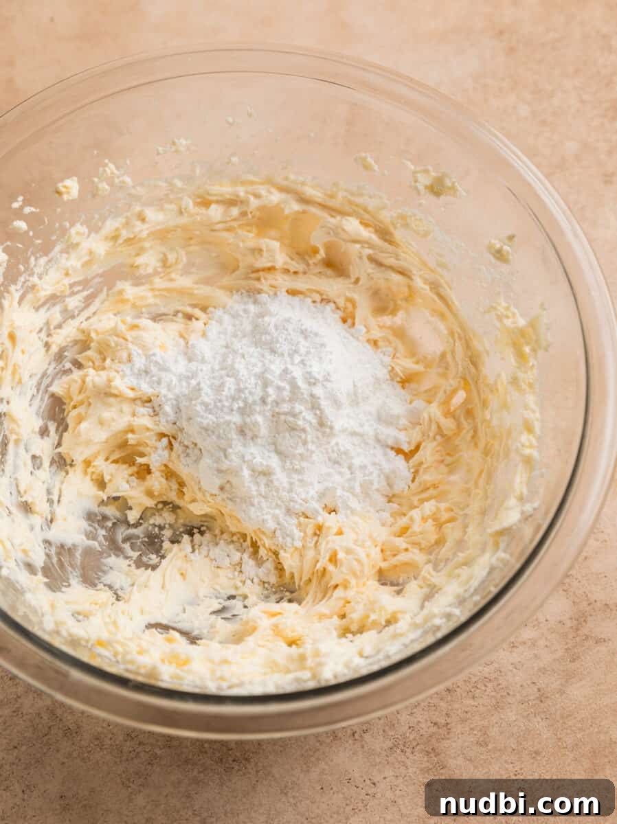 Fluffy Buttermilk Cinnamon Rolls from Scratch 19 Cream cheese frosting mixture in glass bowl with powdered sugar added.