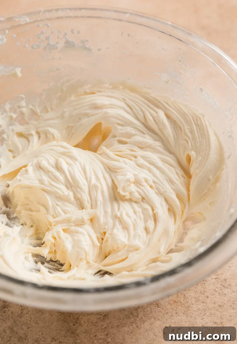Fluffy Buttermilk Cinnamon Rolls from Scratch 20 Cream cheese frosting mixed in glass bowl.