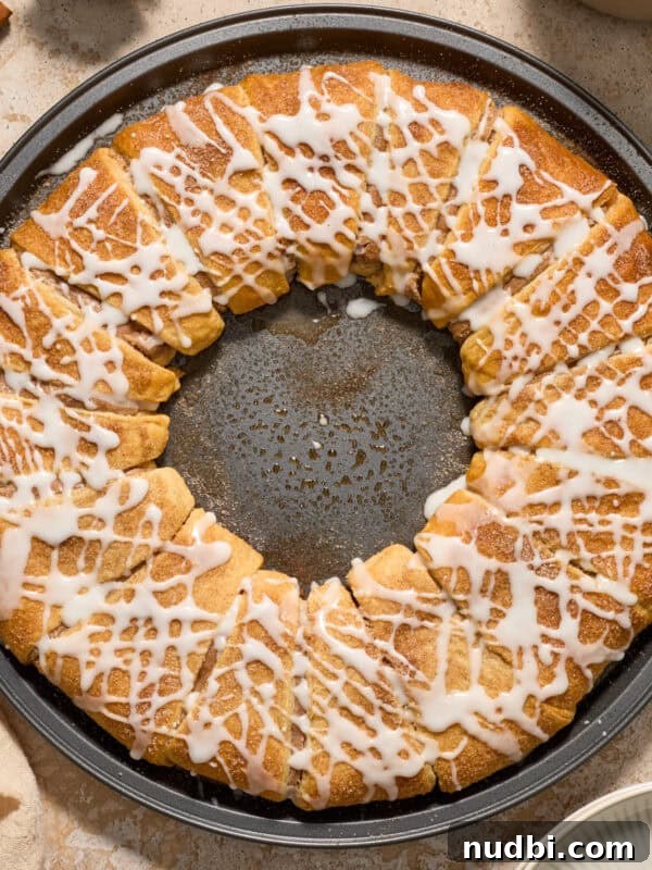 Fluffy Buttermilk Cinnamon Rolls from Scratch 23 Cinnamon crescent wreath on pan with icing drizzle over top.