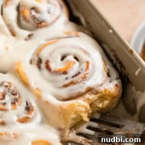 Fluffy Buttermilk Cinnamon Rolls from Scratch 27 Iced buttermilk cinnamon rolls in pan with serving spatula.