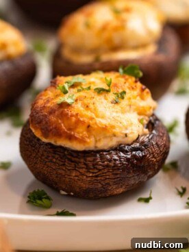 Air fried stuffed mushrooms on white plate topped with chopped parsley.