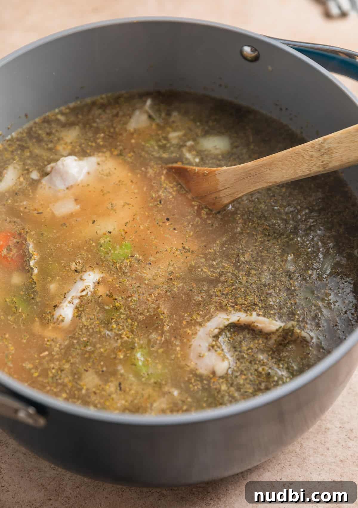 Lemony Chicken Orzo Soup Recipe for Comforting Weeknights 4 Chicken thighs in broth with soup vegetables before cooking.