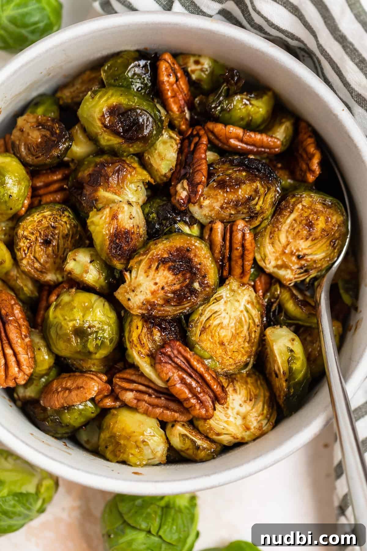 Maple Balsamic Roasted Brussels Sprouts Recipe 2 Serving bowl with roasted maple balsamic brussels sprouts and spoon.