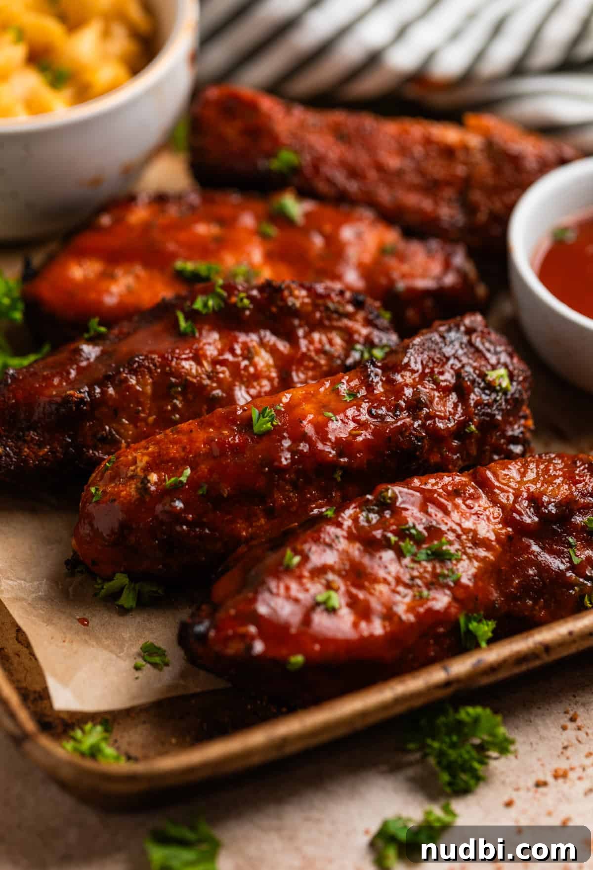 Crispy Air Fryer Country-Style Ribs with Tangy BBQ Glaze 2 Air fryer country style ribs with BBQ sauce on parchment lined tray.