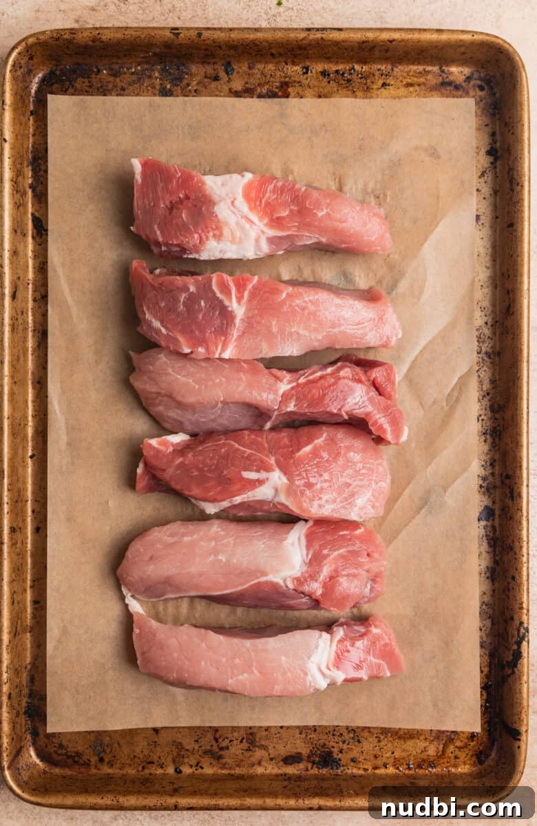 Crispy Air Fryer Country-Style Ribs with Tangy BBQ Glaze 5 Raw pork boneless ribs on parchment lined baking sheet.
