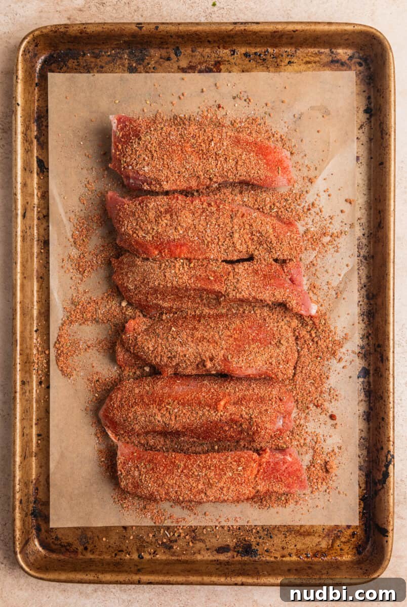 Crispy Air Fryer Country-Style Ribs with Tangy BBQ Glaze 6 Country ribs on parchment lined baking sheet with dry rub covering.