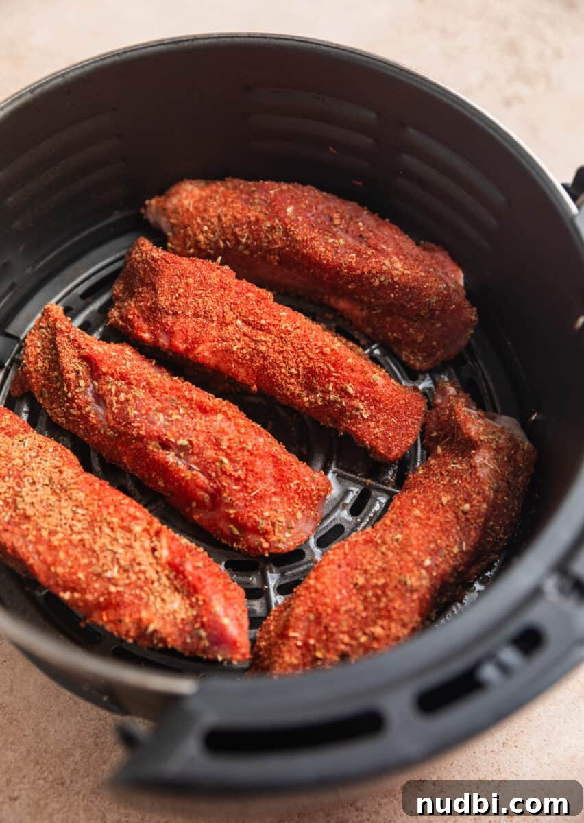 Crispy Air Fryer Country-Style Ribs with Tangy BBQ Glaze 7 Country style ribs with dry rub in oiled air fryer basket.