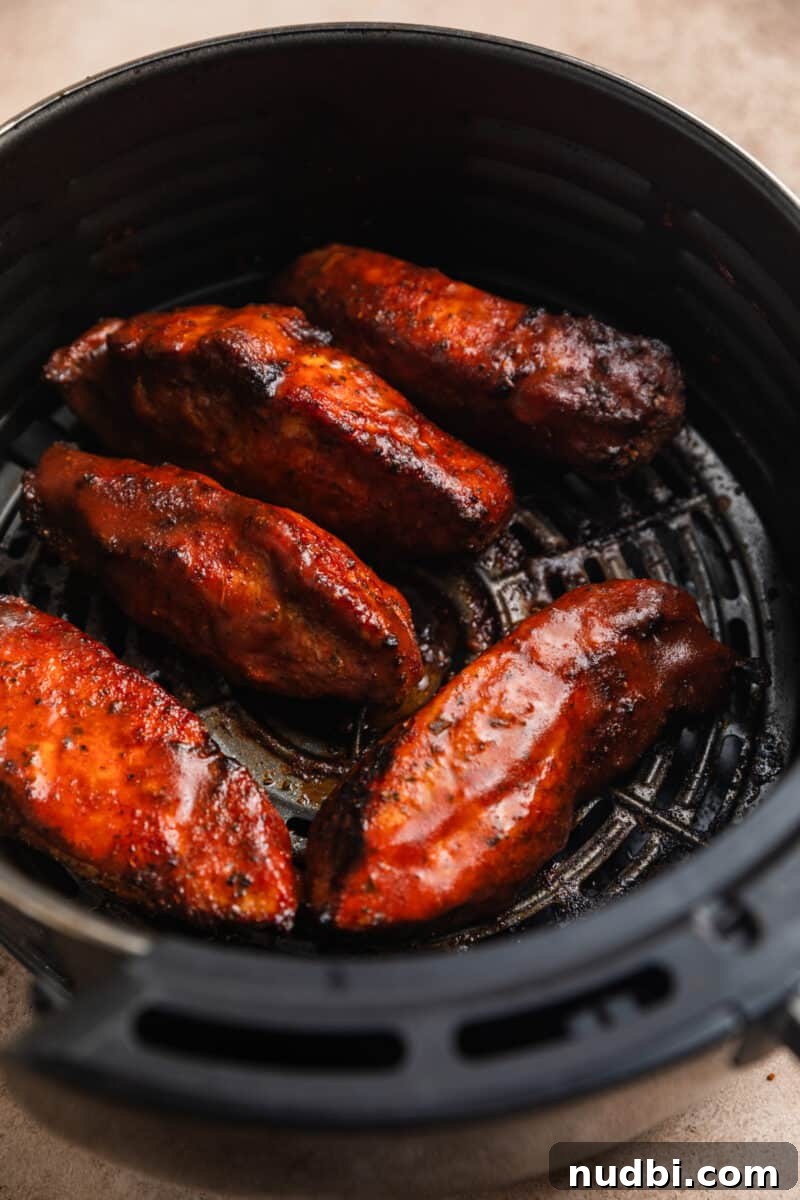 Crispy Air Fryer Country-Style Ribs with Tangy BBQ Glaze 9 Cooked boneless pork ribs in air fryer basket with barbecue sauce.