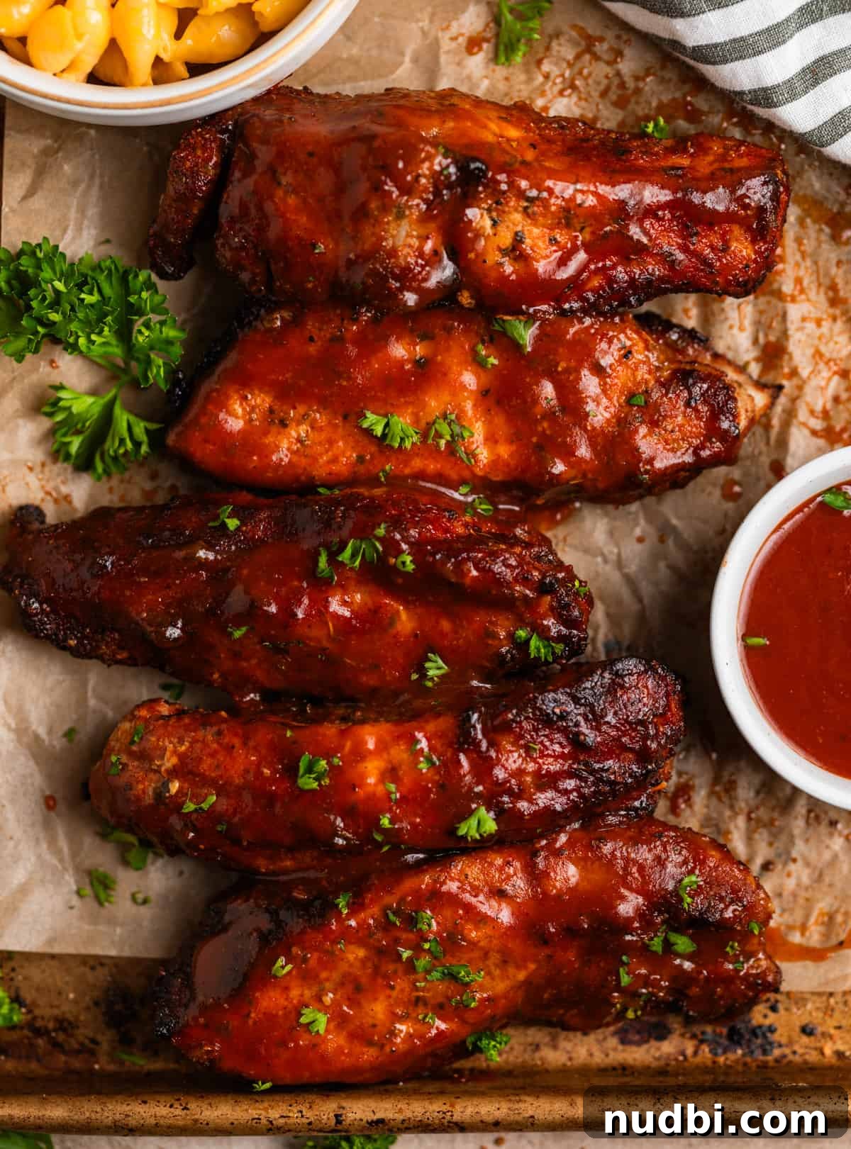 Crispy Air Fryer Country-Style Ribs with Tangy BBQ Glaze 10 BBQ country style ribs on parchment lined baking sheet with macaroni and cheese in dish.