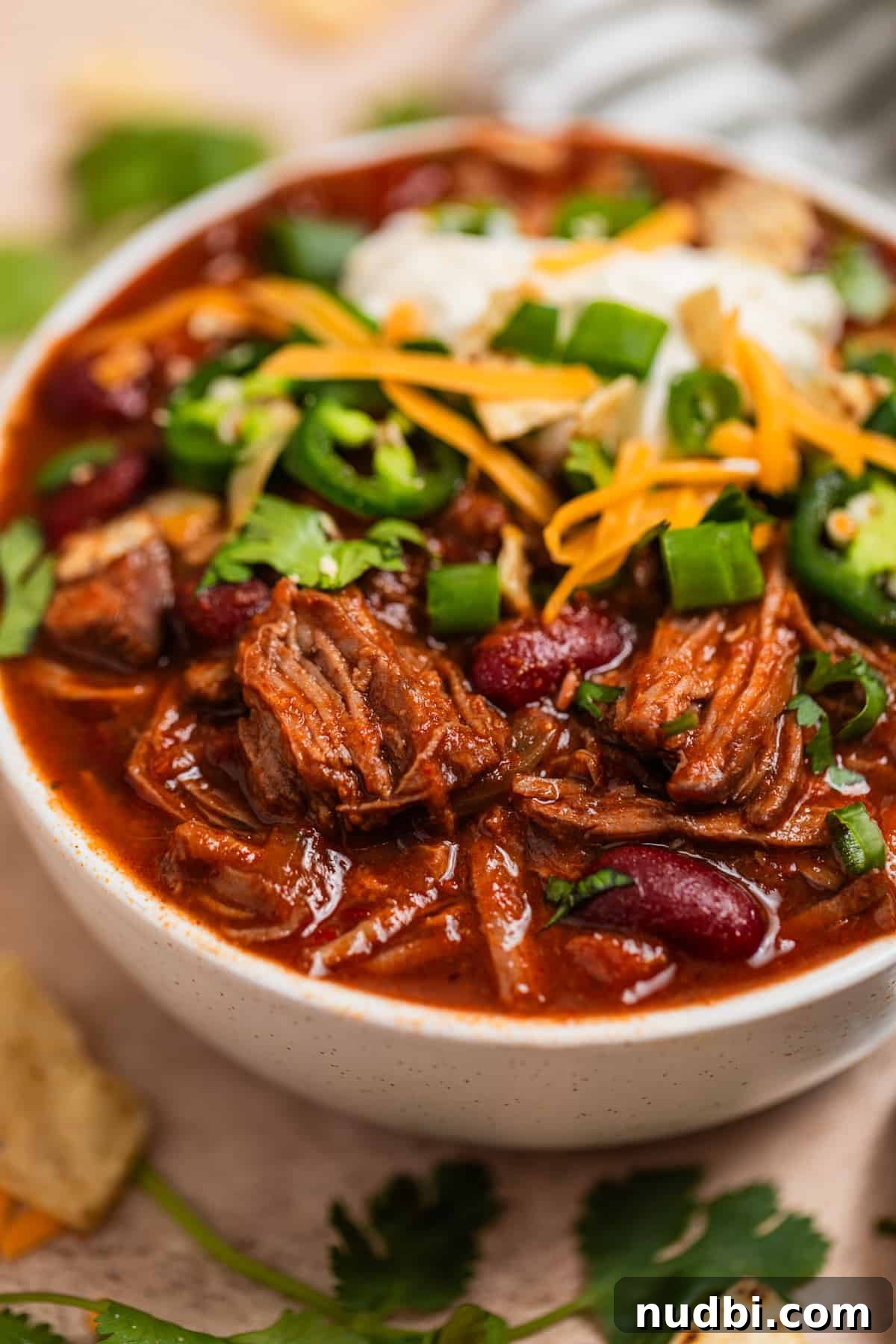 Slow Cooker Shredded Beef Chili Recipe for Comforting Weeknights 3 Bowl of crockpot chili topped with sour cream, cheese and other toppings.