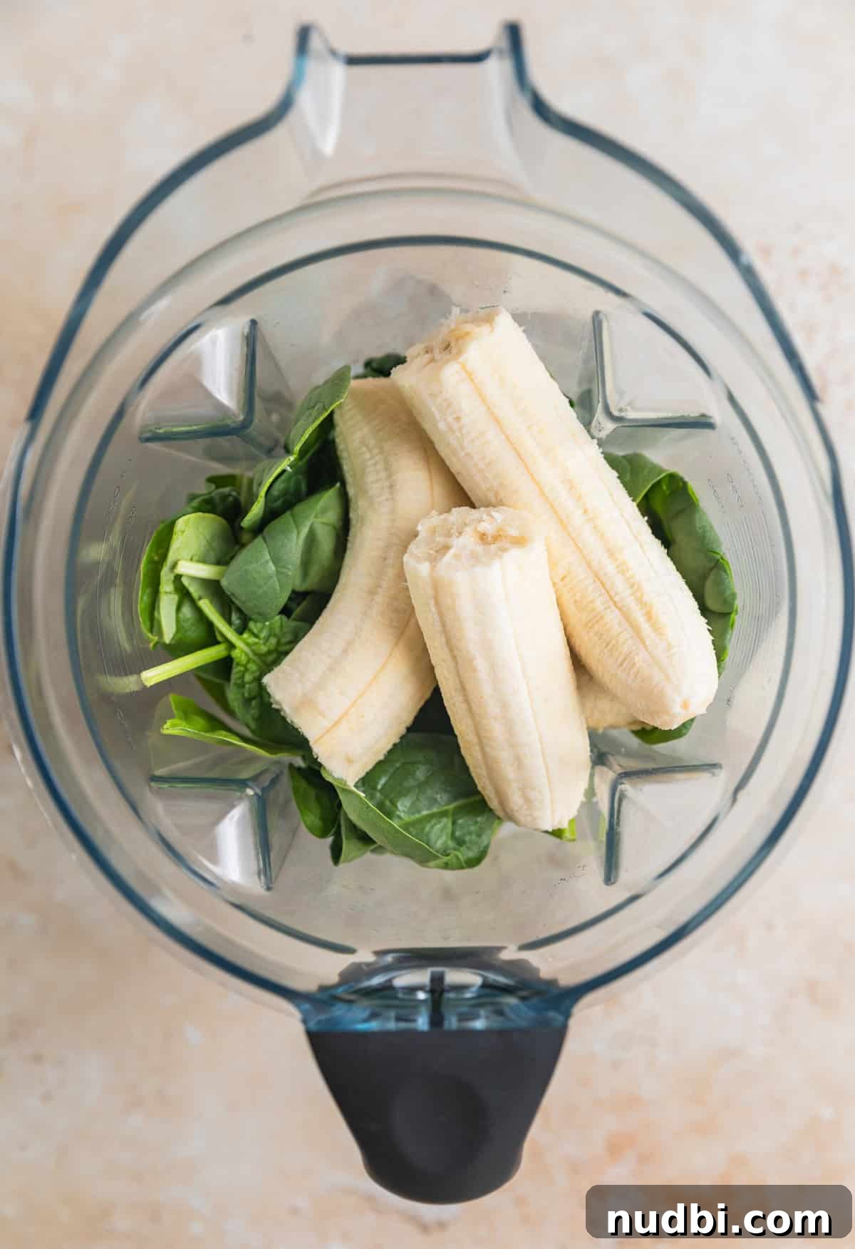Bananas, milk and spinach in blender before being blended.