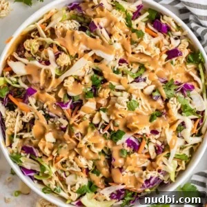 Ramen cabbage salad with peanut dressing over top in white bowl.