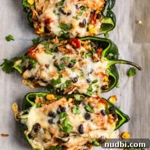 Chicken stuffed poblano peppers on parchment topped with cheese and cilantro.