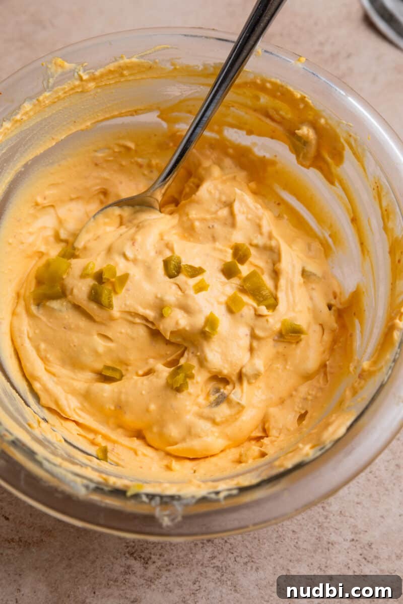 Spicy Deviled Eggs Recipe with Tangy Jalapeño Kick 8 Spicy deviled eggs mixture in glass bowl with spoon.
