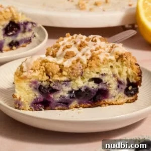 Blueberry Lemon Coffee Cake Recipe — Moist Citrus Bundt Cake 17 Slice of blueberry lemon coffee cake on plate with icing drizzle on top.