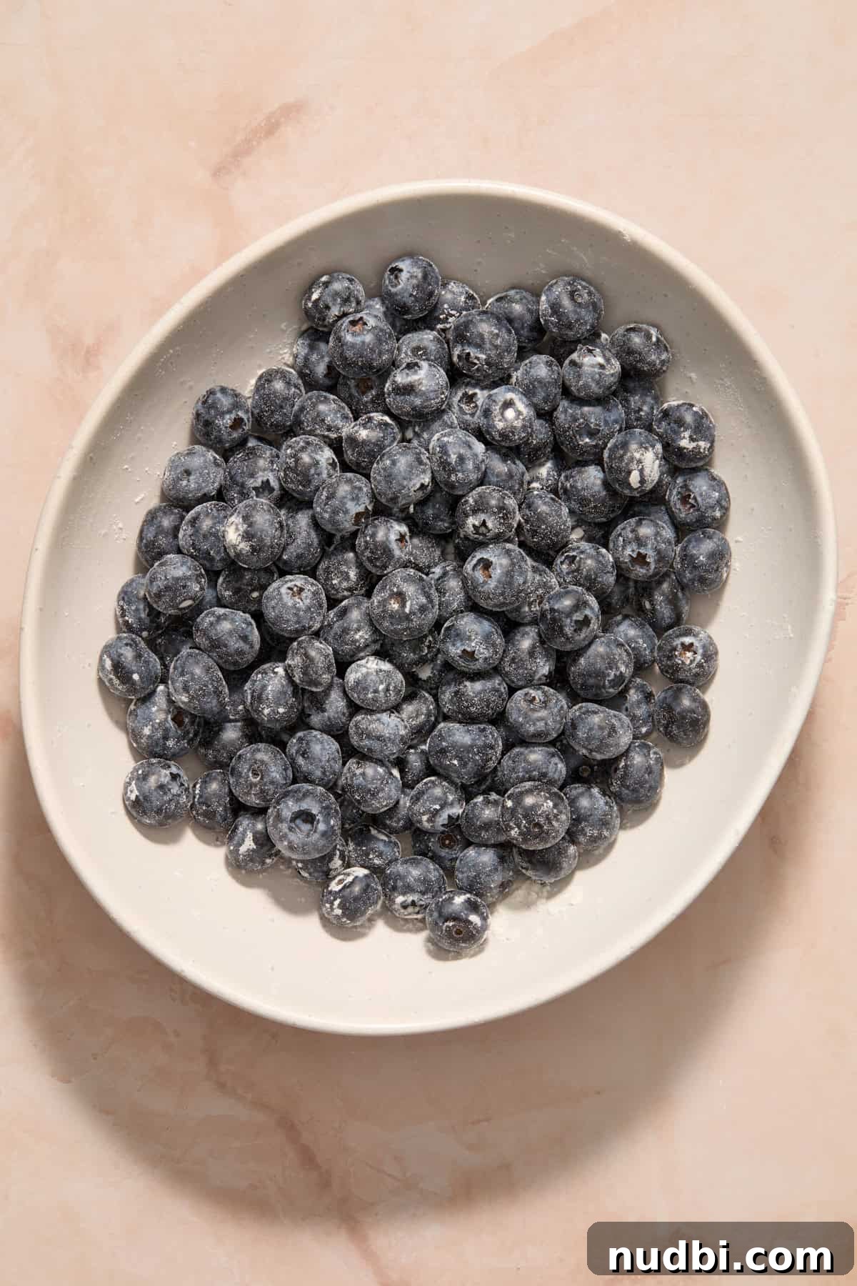 Blueberry Lemon Coffee Cake Recipe — Moist Citrus Bundt Cake 10 Blueberries tossed with flour in bowl.