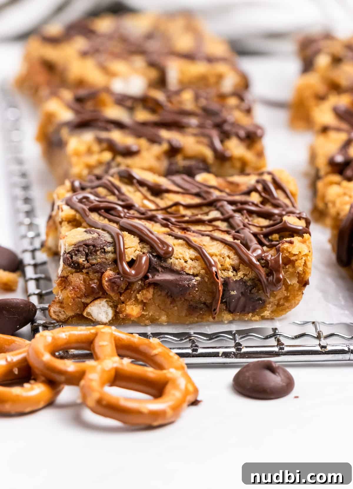 Peanut Butter Chickpea Blondies Recipe — High-Protein Treat 2 Chickpea blondies on wax paper with chocolate drizzle.