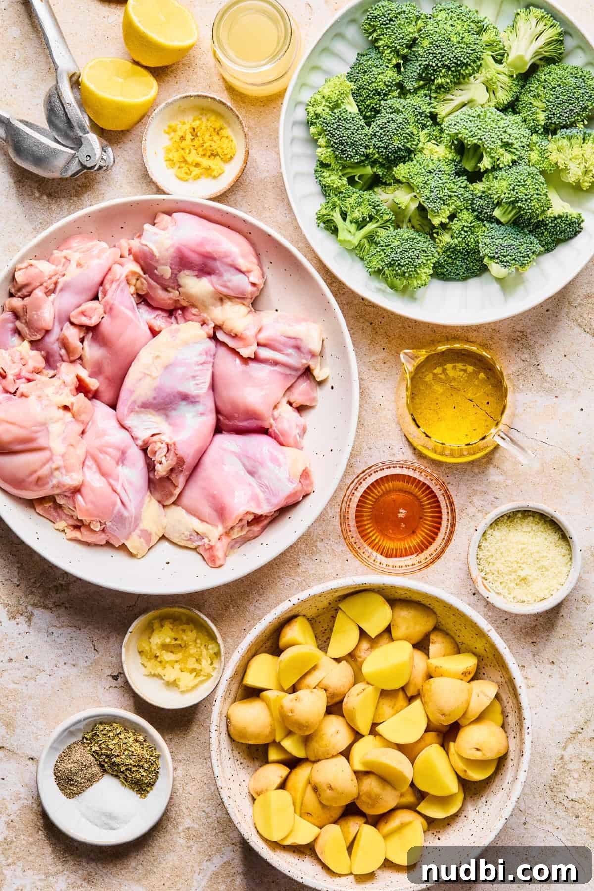 Crispy Lemon Chicken and Roasted Broccoli Sheet Pan Dinner 3 Chicken thighs, broccoli, lemon juice, potatoes and other labeled ingredients on surface.