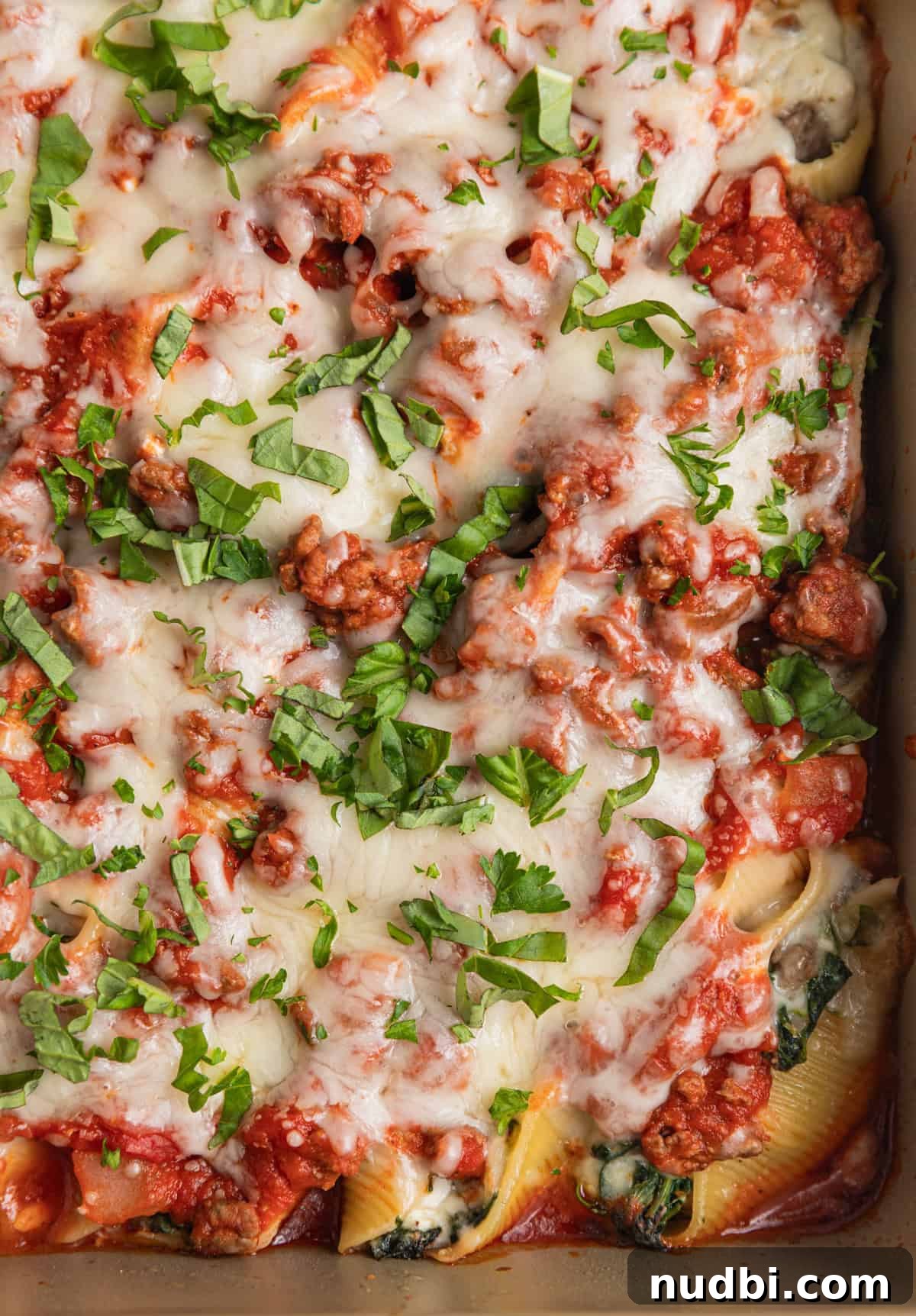 Cheesy Ground Beef Stuffed Shells Recipe for Family Dinners 7 Baked beef stuffed pasta shells in pan topped with freshly chopped herbs.