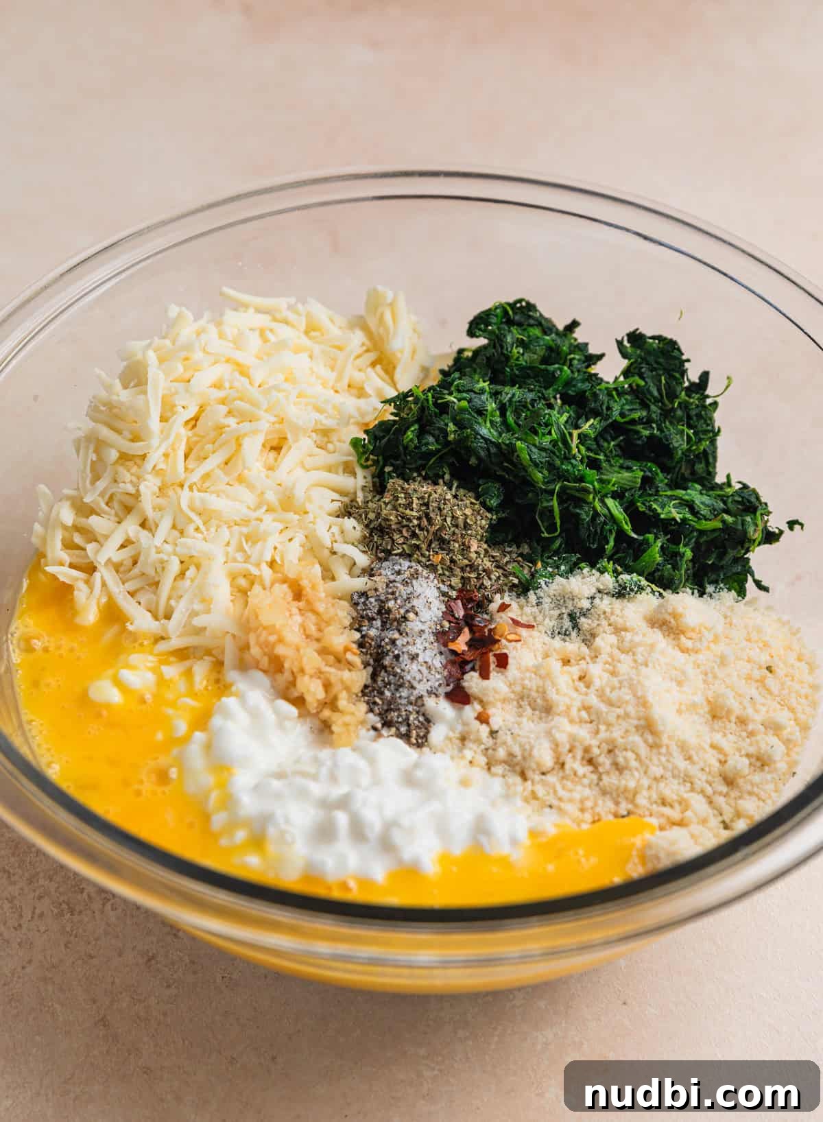 Cheesy Ground Beef Stuffed Shells Recipe for Family Dinners 5 Egg, cottage cheese, mozzarella, spinach, and seasoning in mixing bowl.