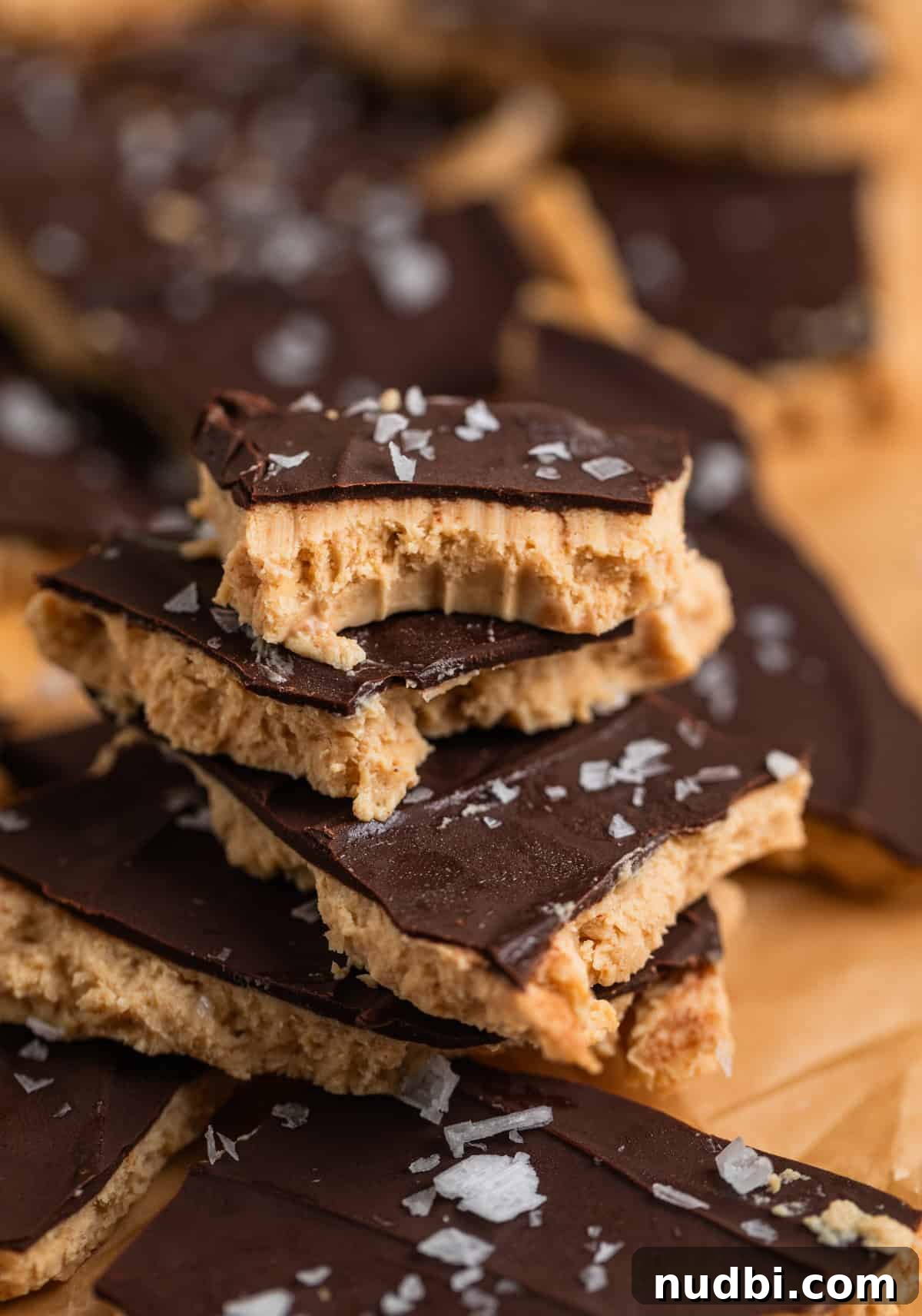 Creamy Greek Yogurt Bark Recipe with Fruit and Honey Toppings 3 Greek yogurt bark with chocolate and sea salt stacked on each other with bite taken out of top piece.